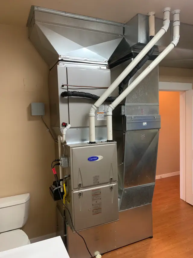 Sheet-metal plenum and PVC flue runs above a new Carrier furnace