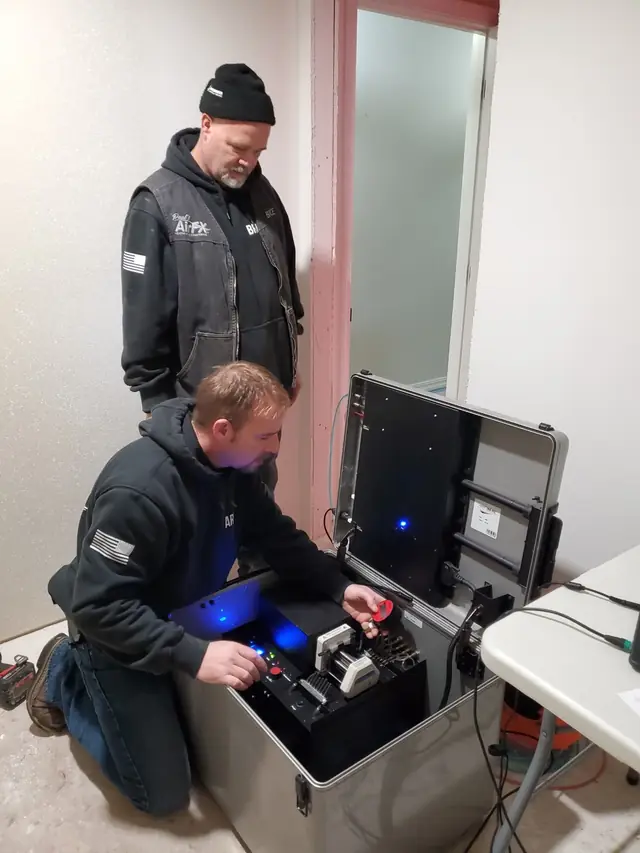 Two Paul's AIR FX technicians running the AeroBarrier sealing rig in a drywalled room